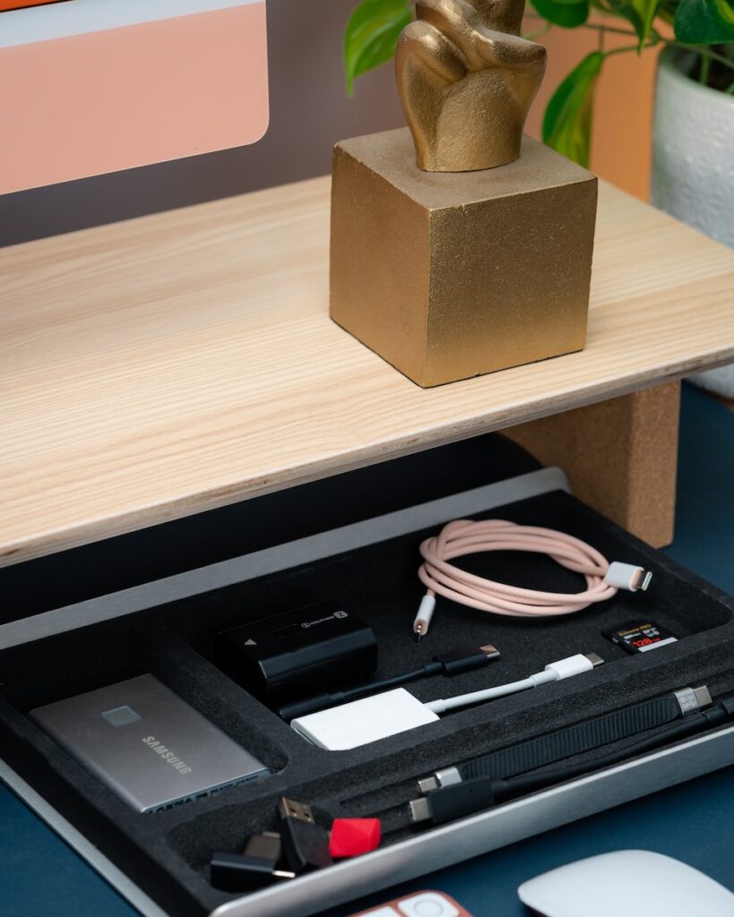 a desk with a laptop, mouse, cell phone and a statue